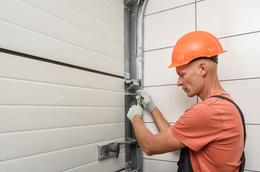 Worker is installing lift gates in the garage. Campbell Garage Door Expert repairing a residential garage door in San Jose, CA