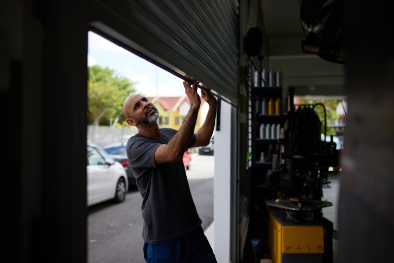 Young man repairing garage door dent in San Jose, CA